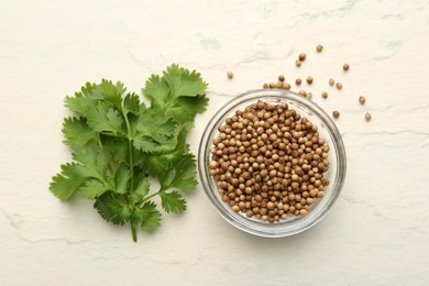 Fresh coriander leaves and dried seeds on light textured table, flat lay