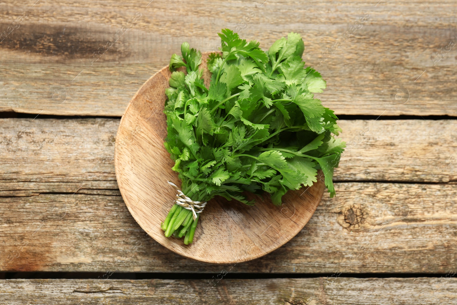 Photo of Bunch of fresh coriander on wooden table, top view