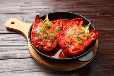 Photo of Tasty stuffed peppers in dish on wooden table