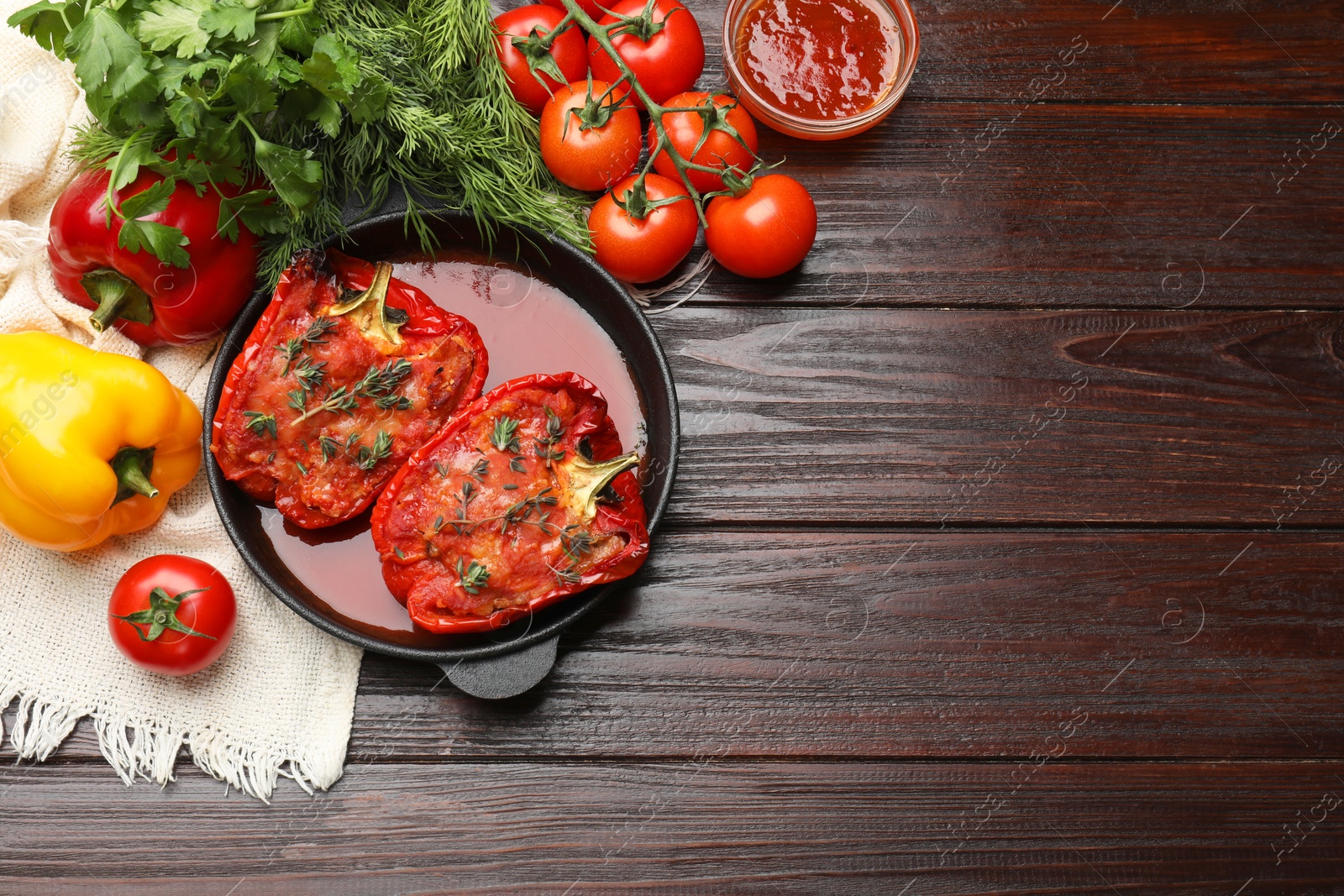 Photo of Tasty stuffed peppers in dish and ingredients on wooden table, flat lay. Space for text