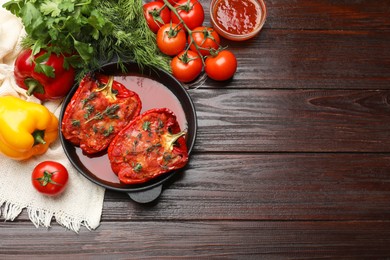 Photo of Tasty stuffed peppers in dish and ingredients on wooden table, flat lay. Space for text