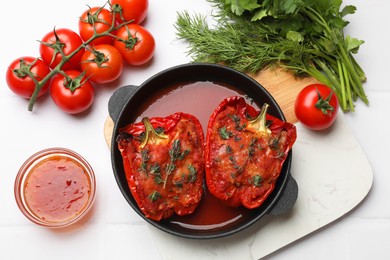 Photo of Tasty stuffed peppers in dish and ingredients on white tiled table, flat lay