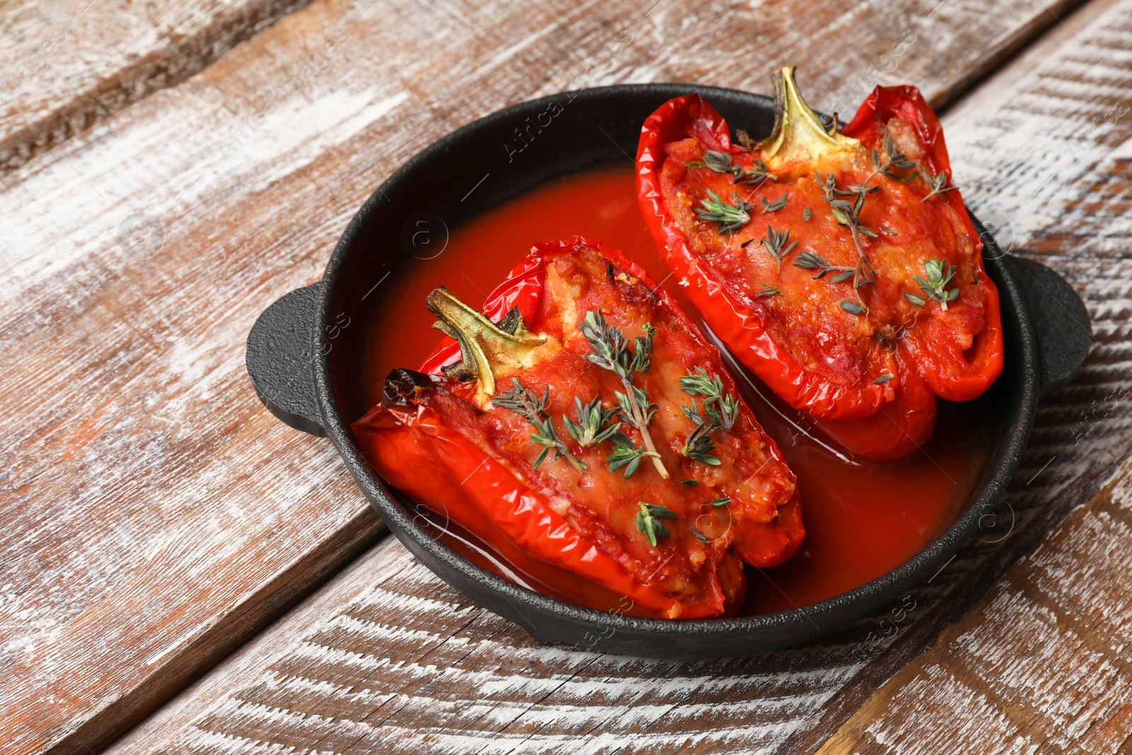 Photo of Tasty stuffed peppers in dish on wooden table