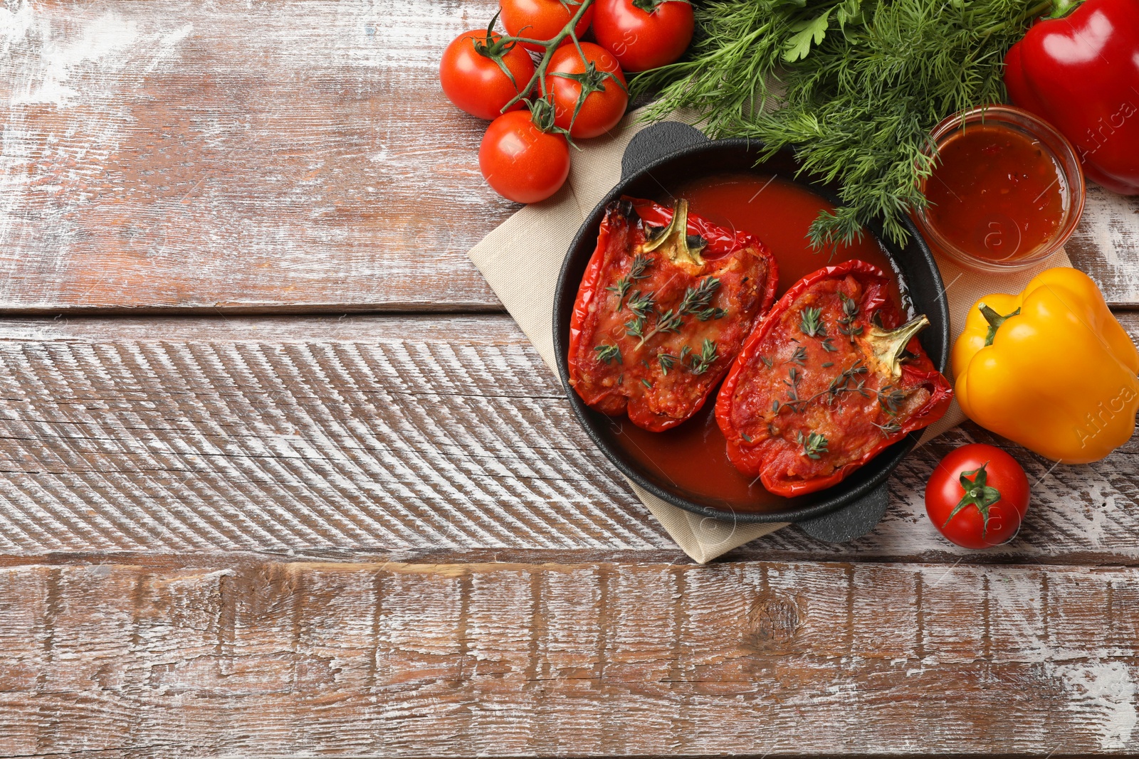 Photo of Tasty stuffed peppers in dish and ingredients on wooden table, flat lay. Space for text