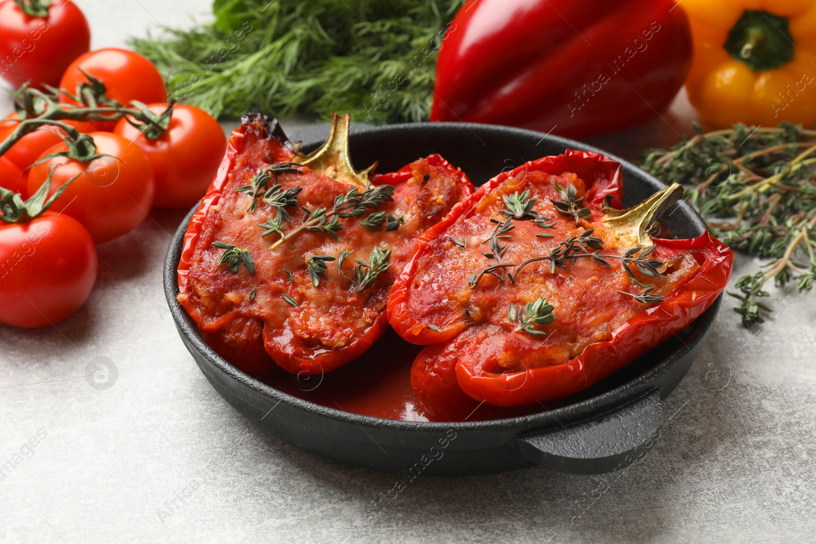 Photo of Tasty stuffed peppers in dish and ingredients on light grey table