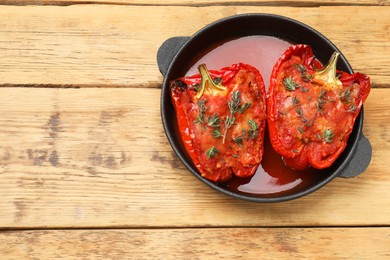 Photo of Tasty stuffed peppers in dish on wooden table, top view. Space for text