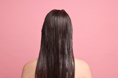 Woman with hair mask on pink background, back view