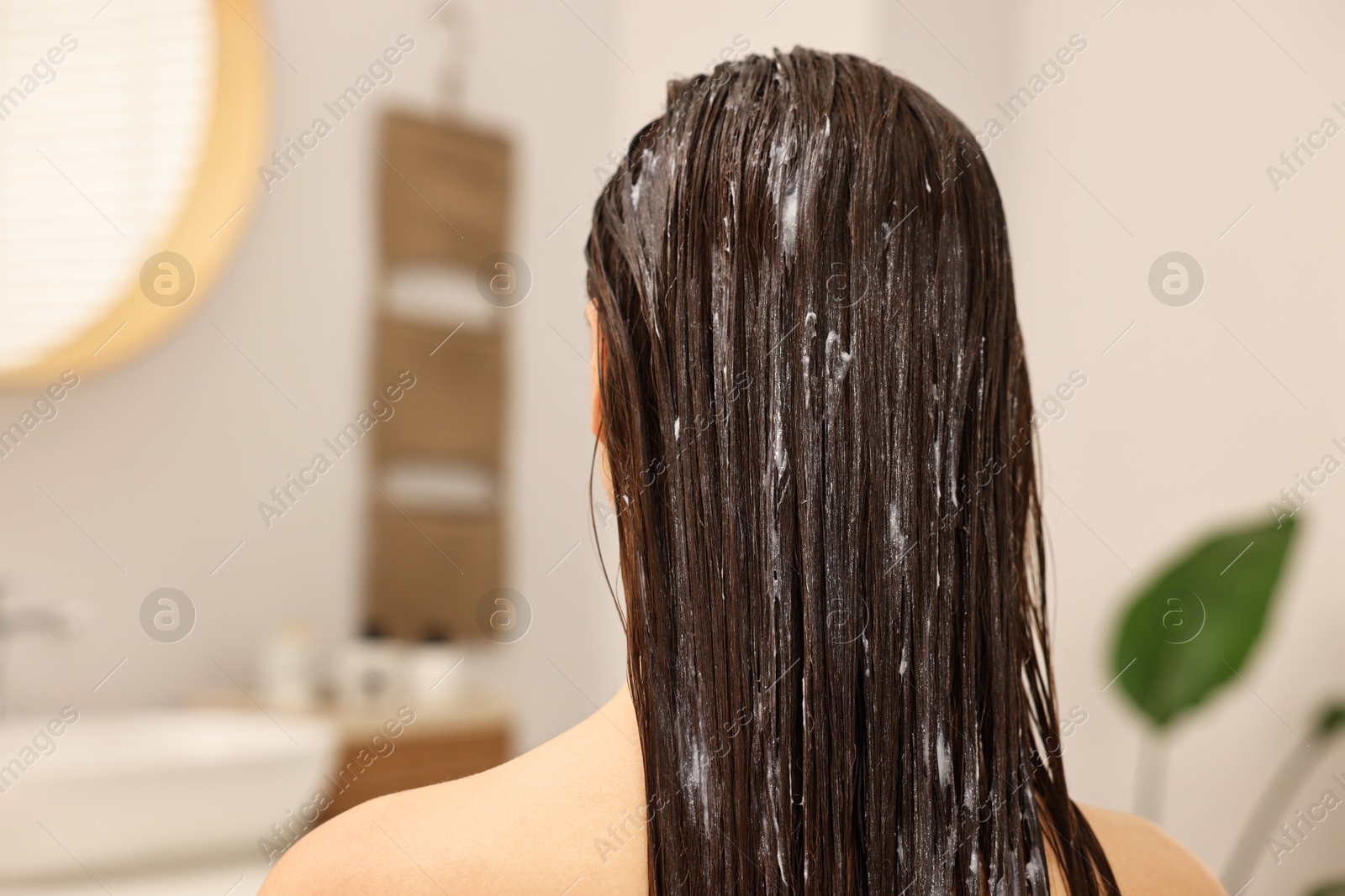 Photo of Woman with hair mask in bathroom, back view