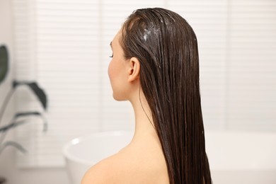 Photo of Woman with cosmetic hair mask in bathroom
