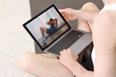 Photo of Online fitness trainer. Man watching tutorial on laptop indoors, closeup