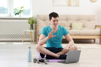 Photo of Online fitness trainer. Man having video chat via laptop at home