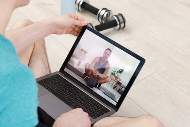 Online fitness trainer. Man watching tutorial on laptop indoors, closeup