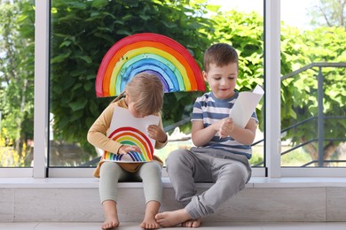 Photo of Children with pictures of rainbow near window indoors