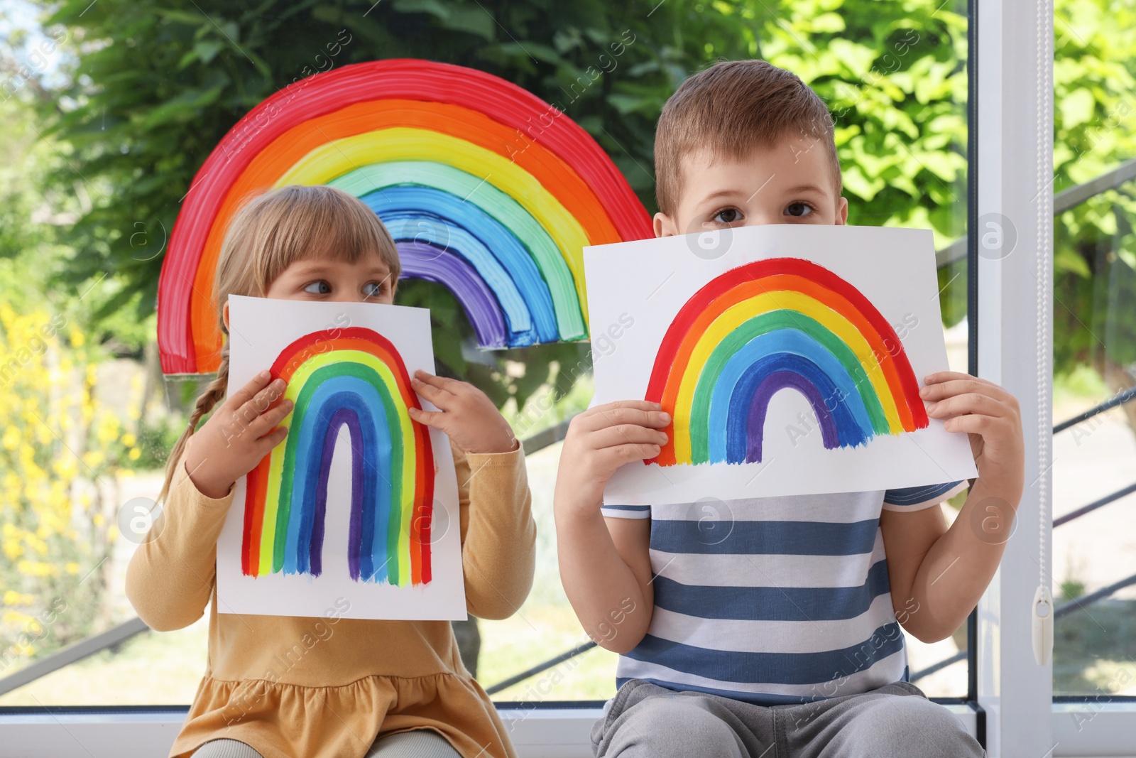 Photo of Children with pictures of rainbow near window indoors