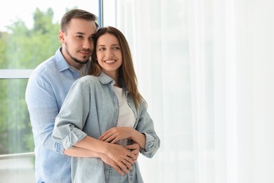 Photo of Happy couple hugging at home. Space for text