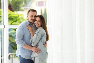 Photo of Cute couple hugging at home. Space for text