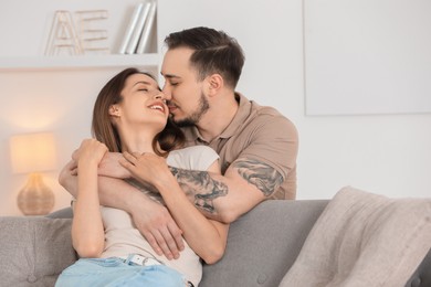 Man hugging his happy girlfriend on sofa at home