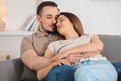 Photo of Cute couple hugging on sofa at home