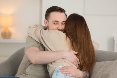 Photo of Cute couple hugging on sofa at home