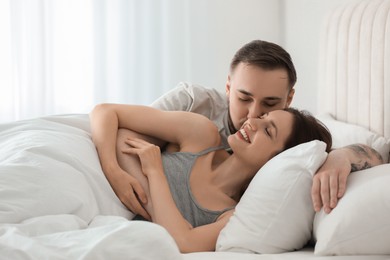 Happy couple enjoying each other in bed at home