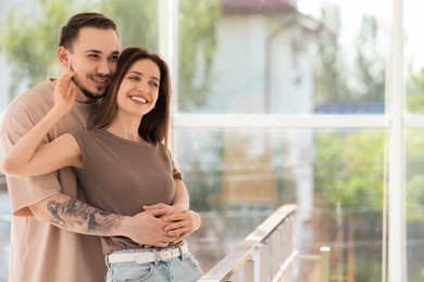 Photo of Happy couple hugging at home. Space for text