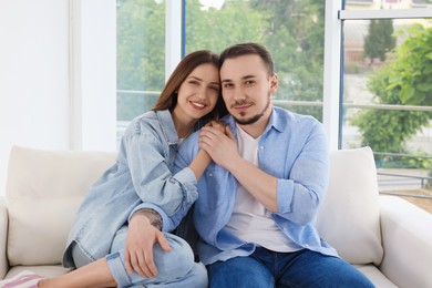 Photo of Happy couple holding hands on sofa at home