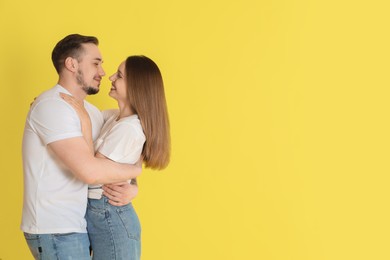Photo of Happy couple hugging on yellow background. Space for text