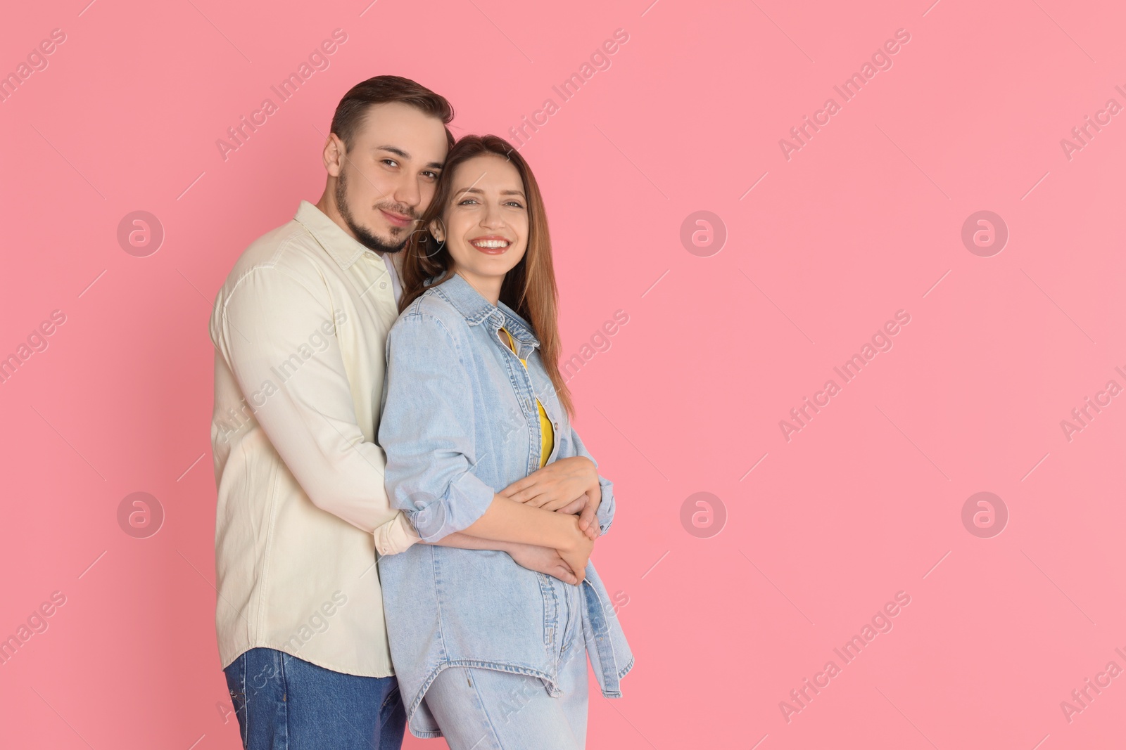 Photo of Cute couple hugging on pink background. Space for text