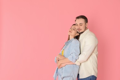 Photo of Cute couple hugging on pink background. Space for text