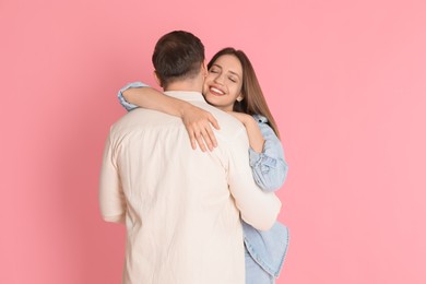 Photo of Smiling woman hugging her boyfriend on pink background