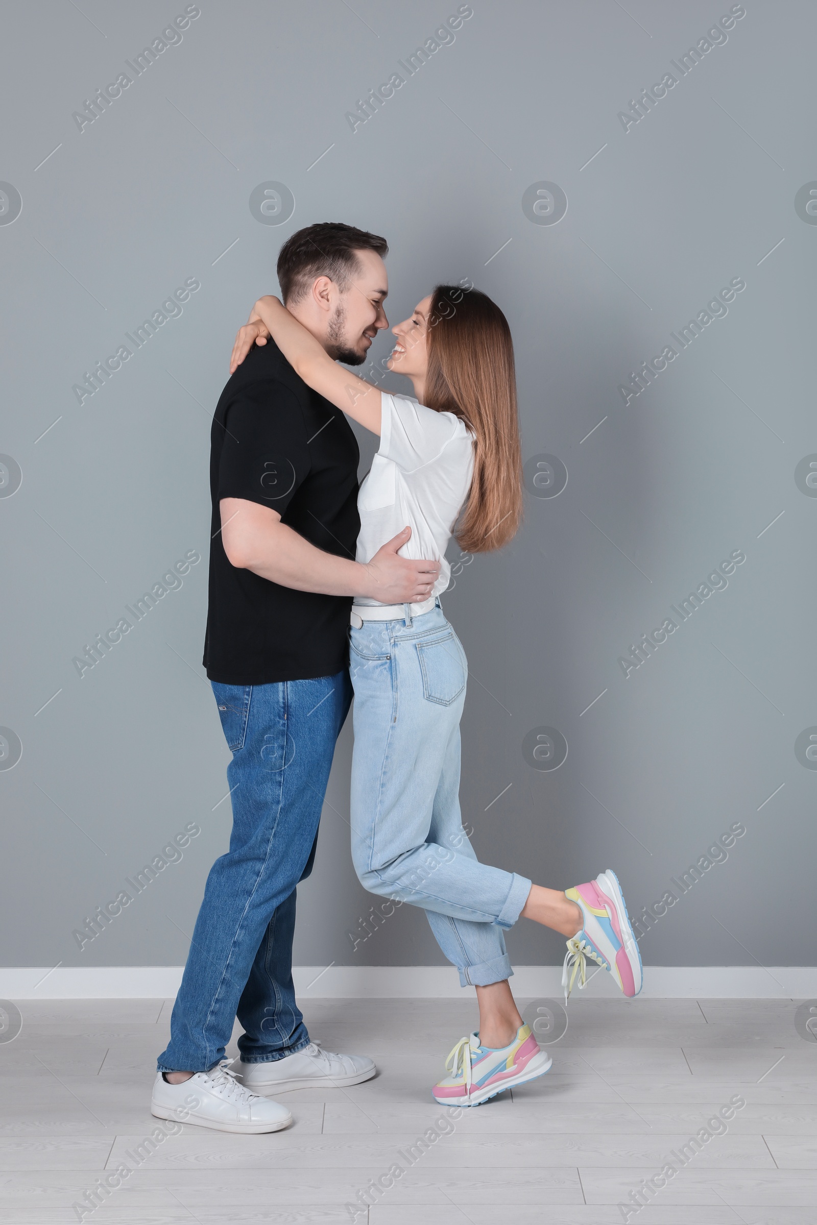 Photo of Happy couple hugging near grey wall. Strong relationship