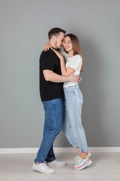 Photo of Happy couple hugging near grey wall. Strong relationship
