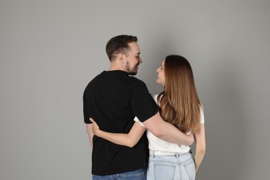 Photo of Cute couple hugging on grey background, back view