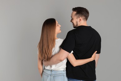 Photo of Cute couple hugging on grey background, back view. Space for text