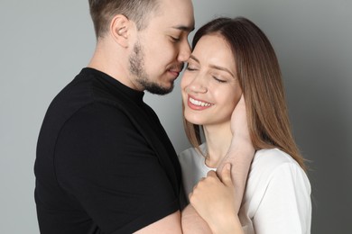 Photo of Man hugging and kissing his happy girlfriend on grey background