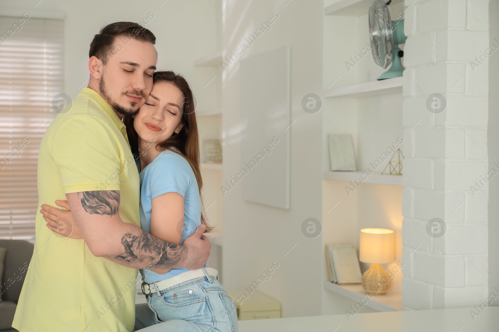 Photo of Cute couple hugging at home. Space for text