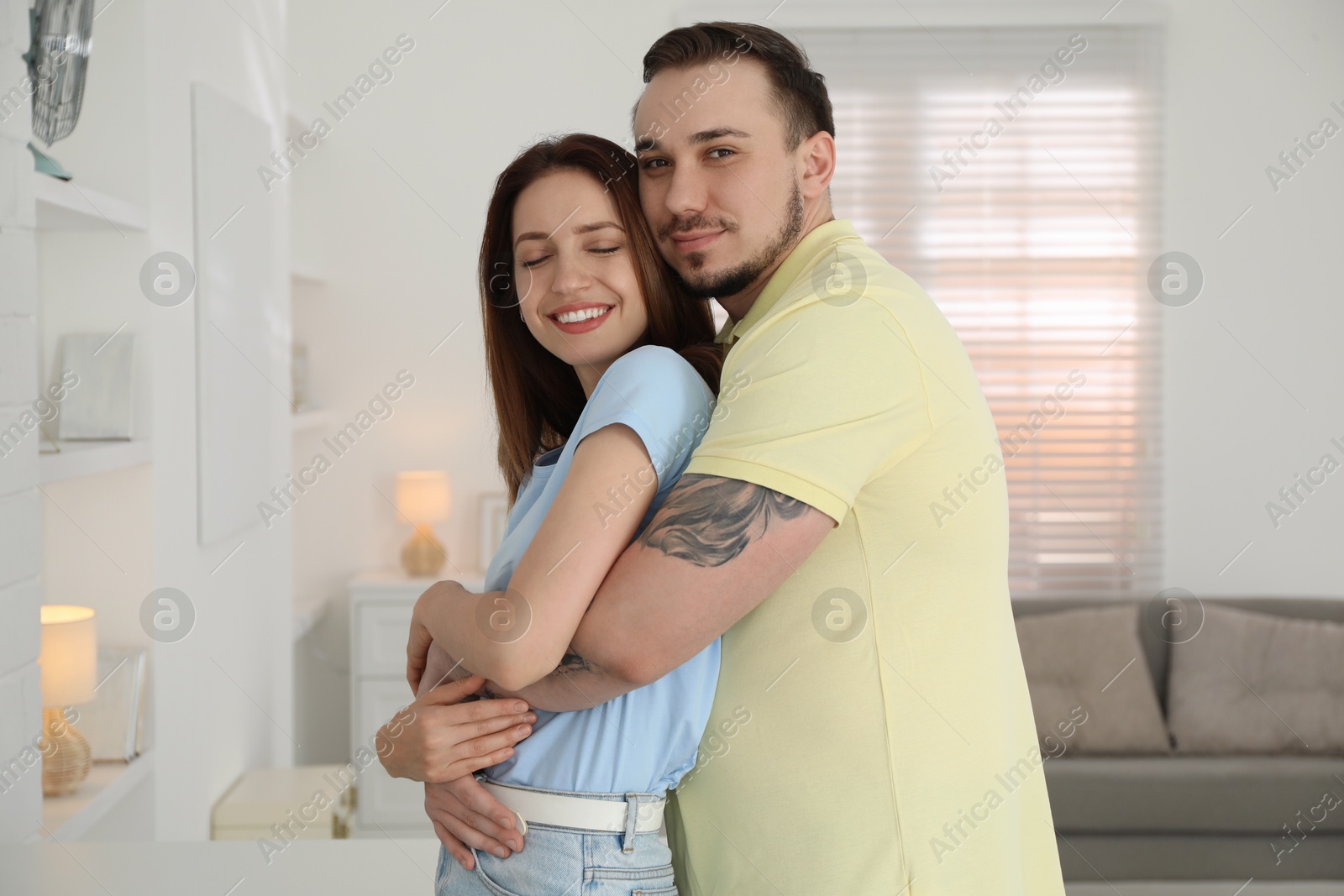 Photo of Man hugging his happy girlfriend at home