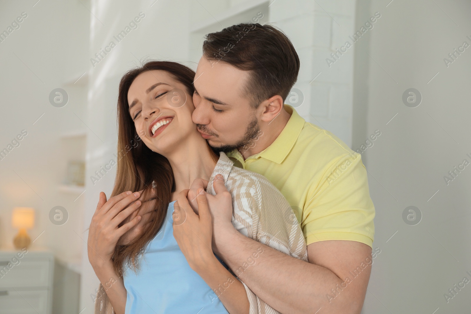 Photo of Man kissing his happy girlfriend at home