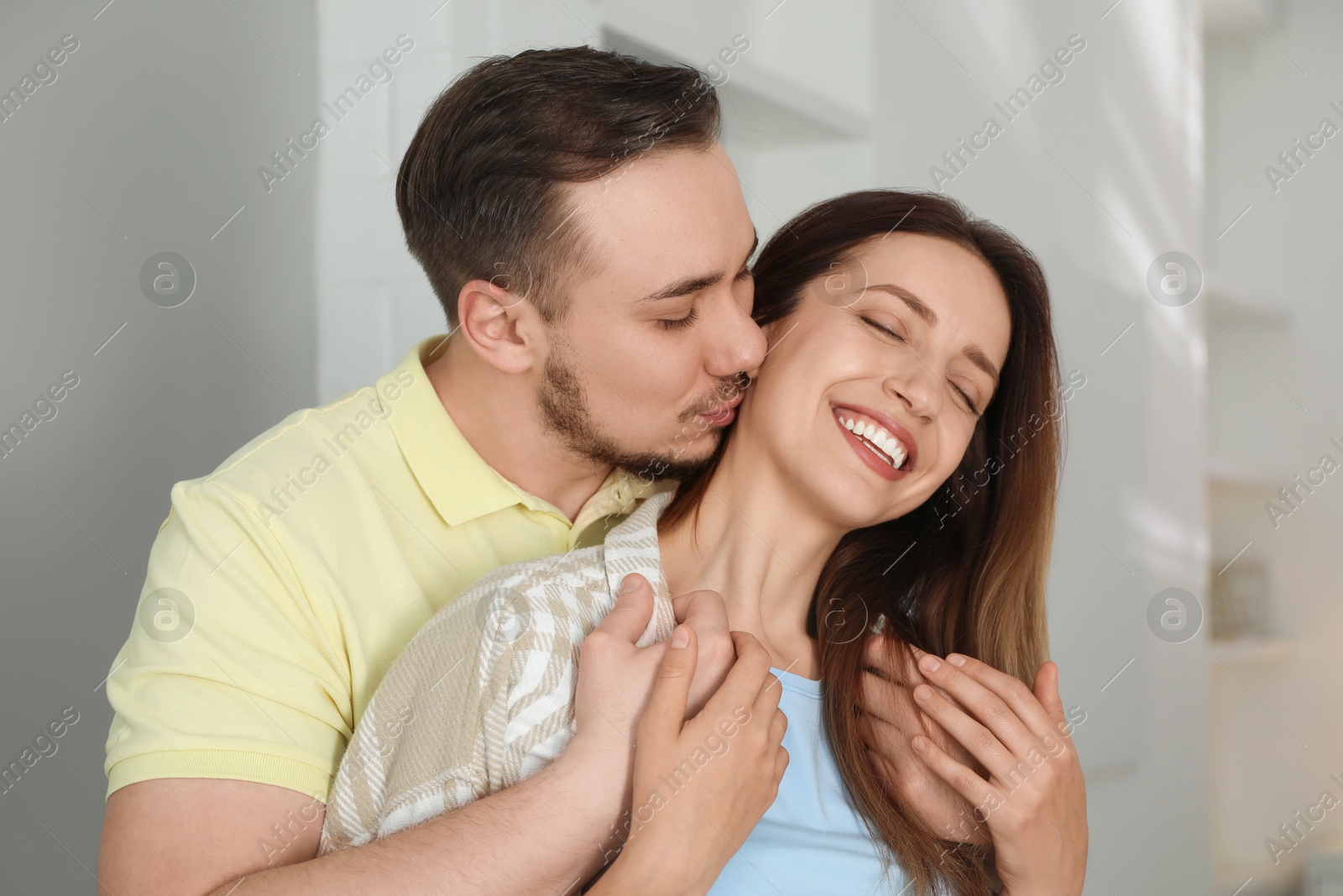 Photo of Man kissing his happy girlfriend at home
