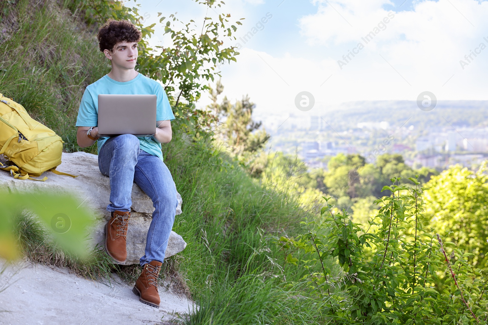 Photo of Travel blogger using laptop on stone outdoors, space for text