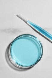 Pipette and petri dish with liquid on white marble table, flat lay