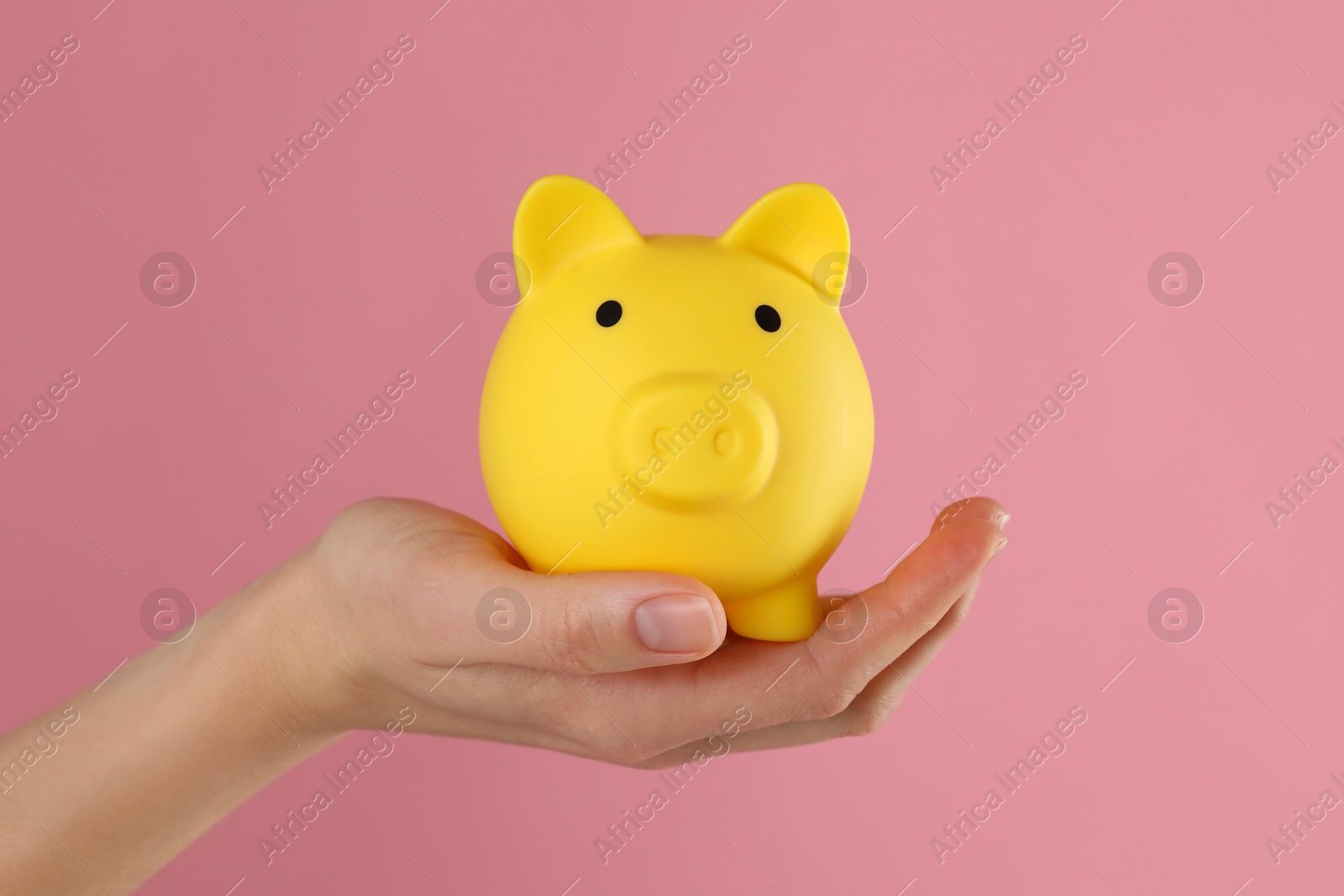 Photo of Woman with yellow piggy bank on pink background, closeup