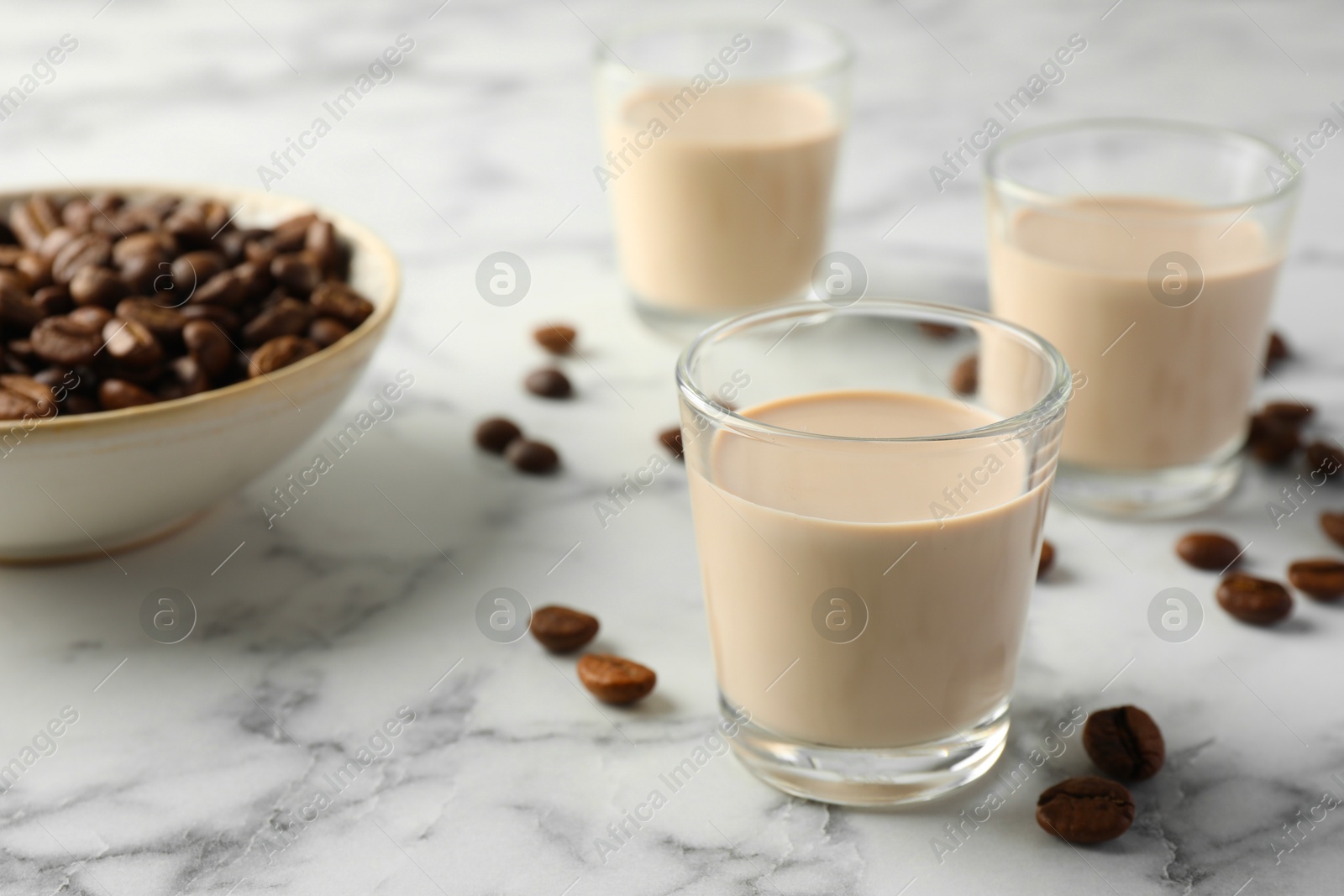 Photo of Coffee cream liqueur in glasses and beans on white marble table