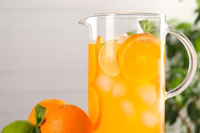 Photo of Freshly made lemonade in jug and citrus fruits against blurred background