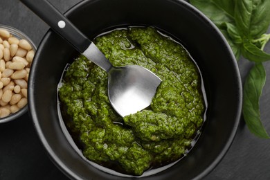 Photo of Taking tasty pesto sauce at black table, top view