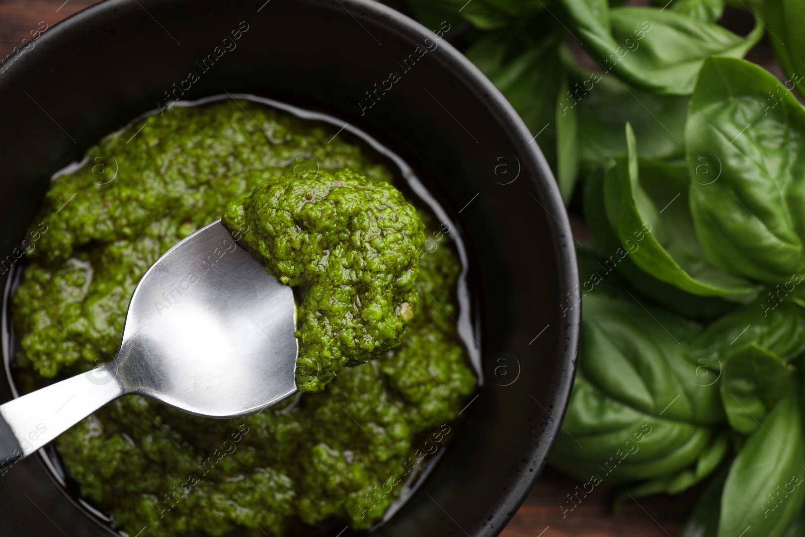 Photo of Taking tasty pesto sauce at table, top view