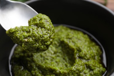 Photo of Taking tasty pesto sauce at table, closeup