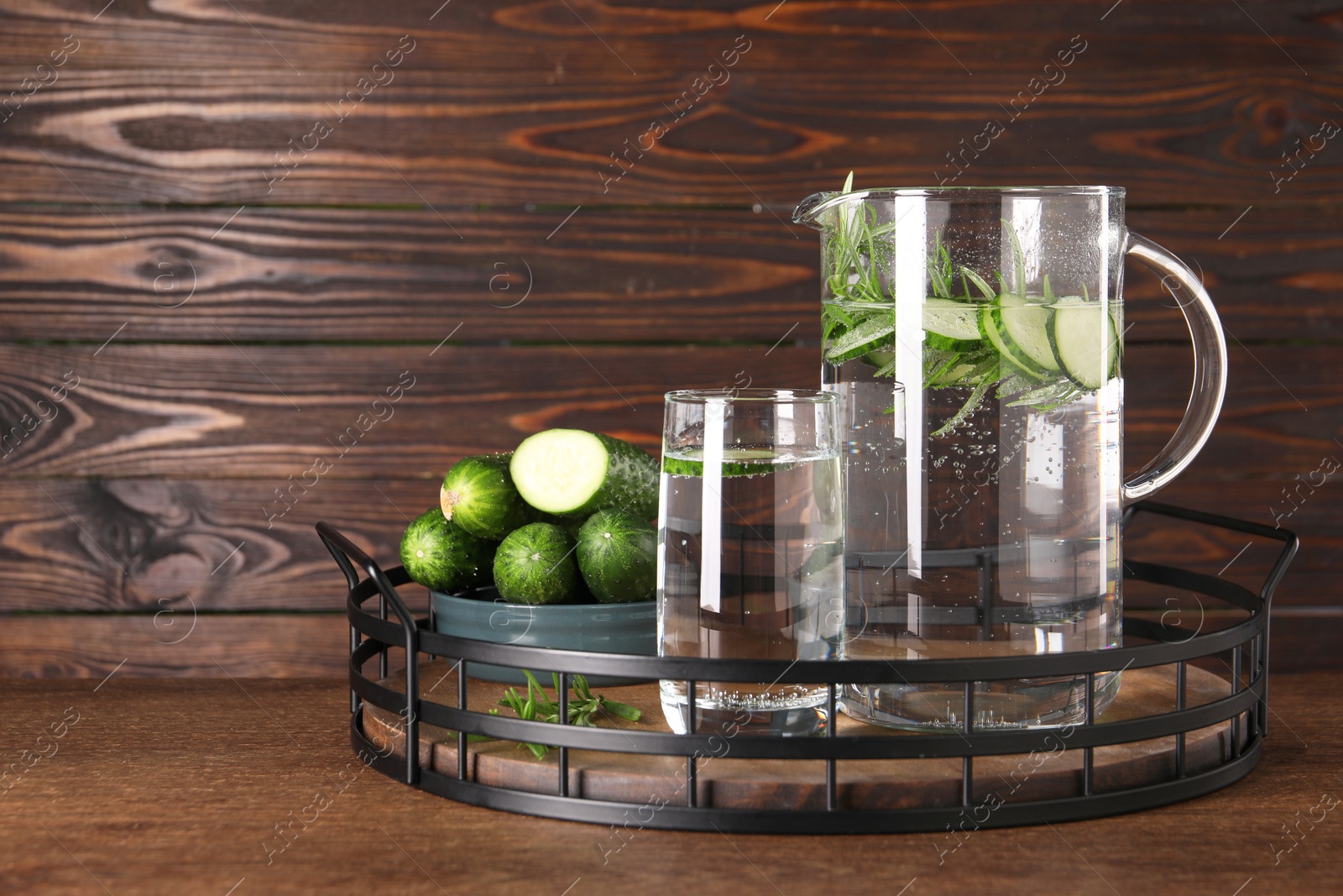 Photo of Tray with refreshing cucumber water with rosemary and vegetable on wooden table. Space for text