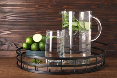 Tray with refreshing cucumber water with rosemary and vegetable on wooden table