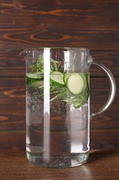 Refreshing cucumber water with rosemary in jug on wooden table